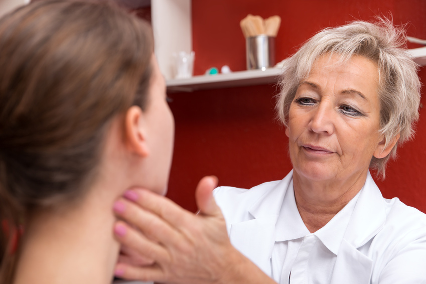 Ärztin untersucht die Lymphknoten am Hals einer jungen Frau