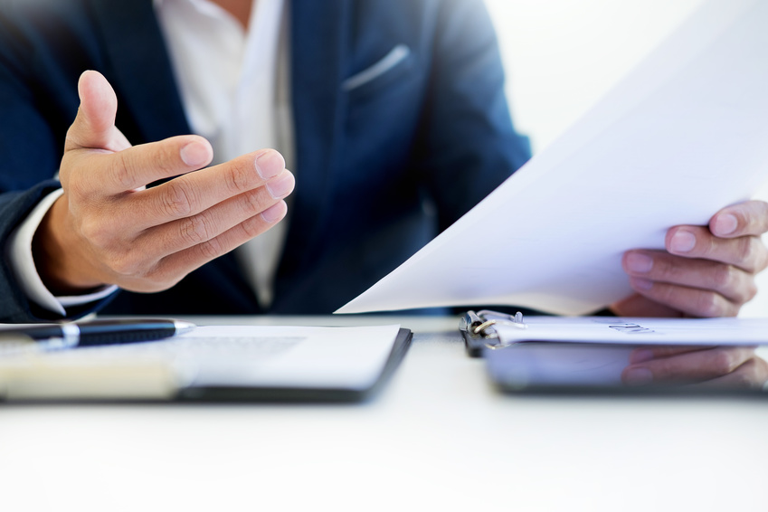 Man signing a car insurance policy, the agent is holding the document
